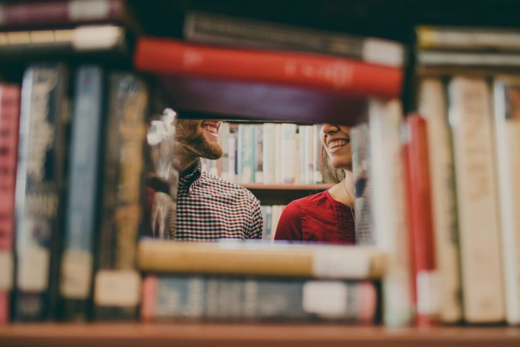 Kaksi ihmistä seisoo kirjojen takana.