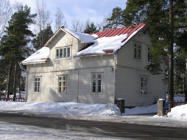 Vaalea talo lumisessa maisemassa.