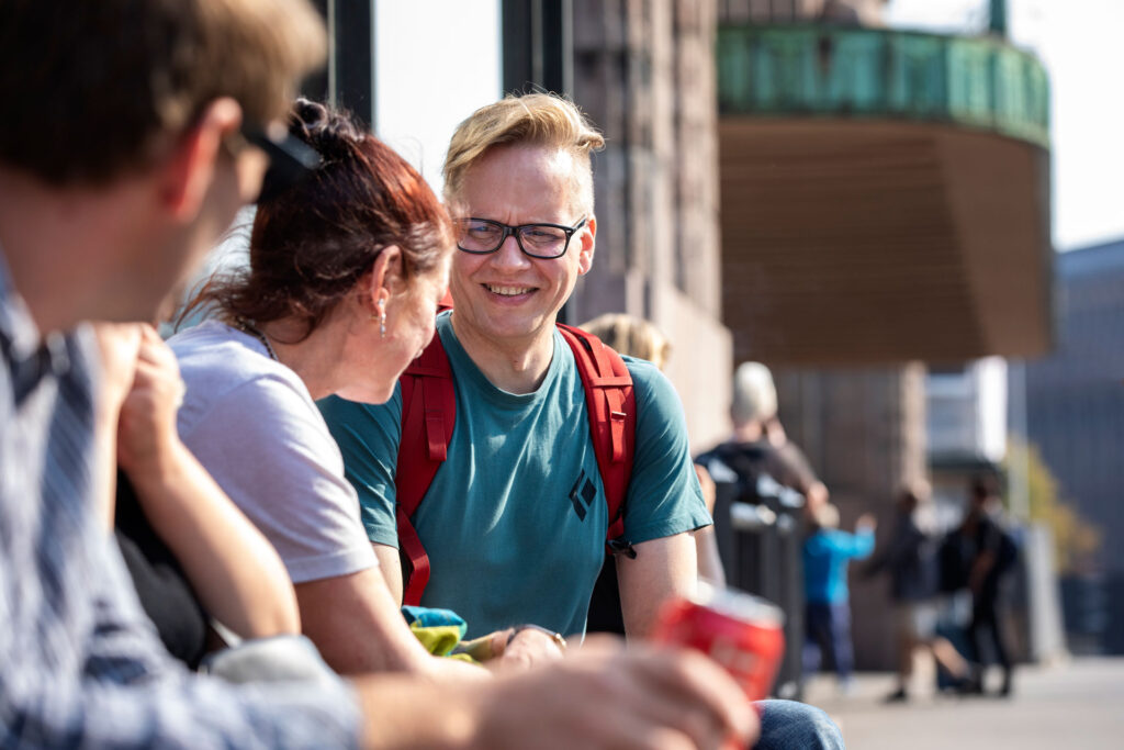 Vaaleahiuksinen mies keskustelee selin kameraan olevan henkilön kanssa.