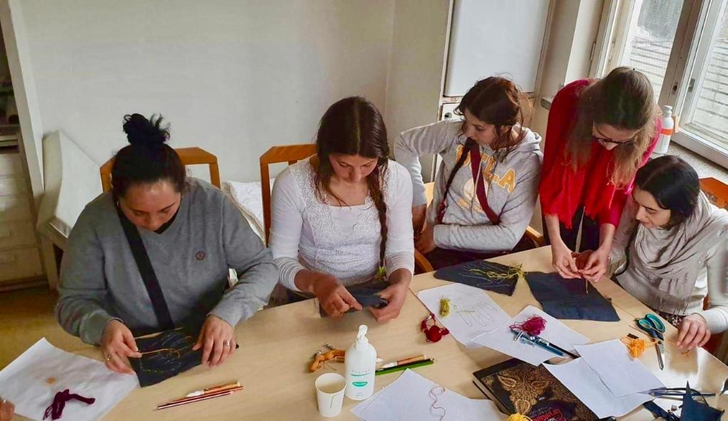 Five women sitting around a table doing crafts.